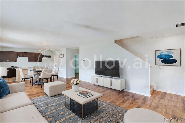 living room with stairs, baseboards, visible vents, and light wood-style floors