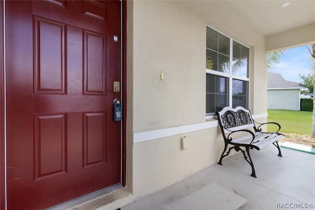 view of exterior entry with covered porch and stucco siding