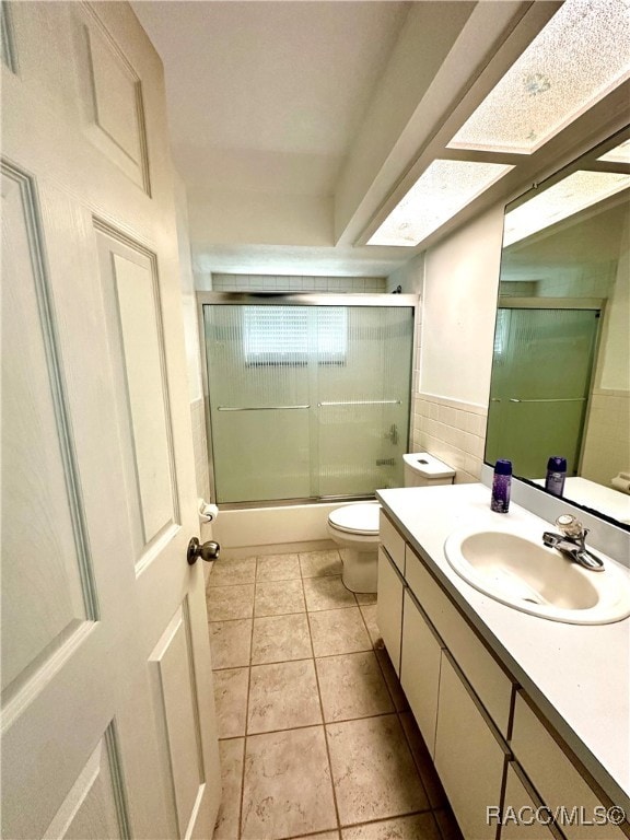 full bathroom with vanity, tile walls, enclosed tub / shower combo, tile patterned flooring, and toilet