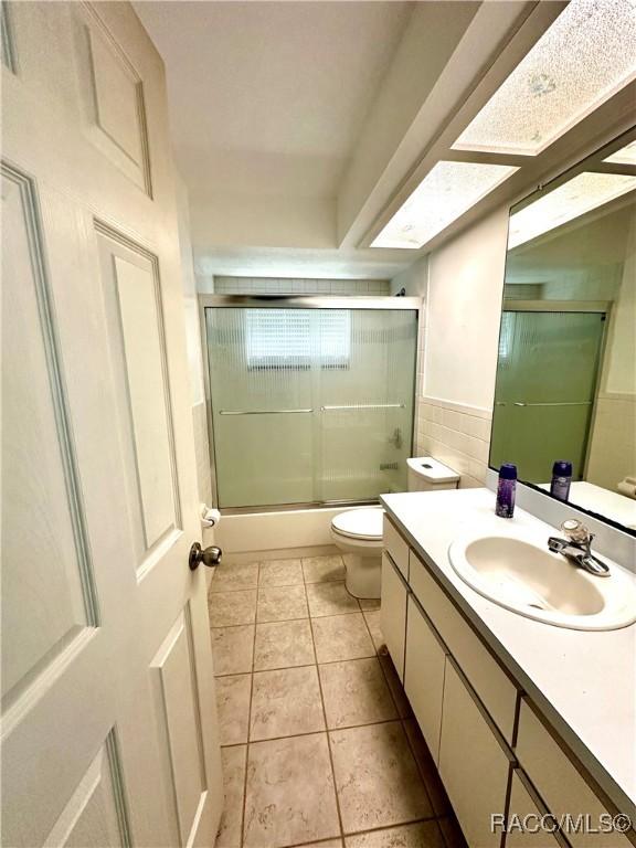 3150 W Mustang Blvd, Beverly Hills, FL 34465 - full bathroom featuring toilet, vanity, enclosed tub / shower combo, tile patterned flooring, and tile walls