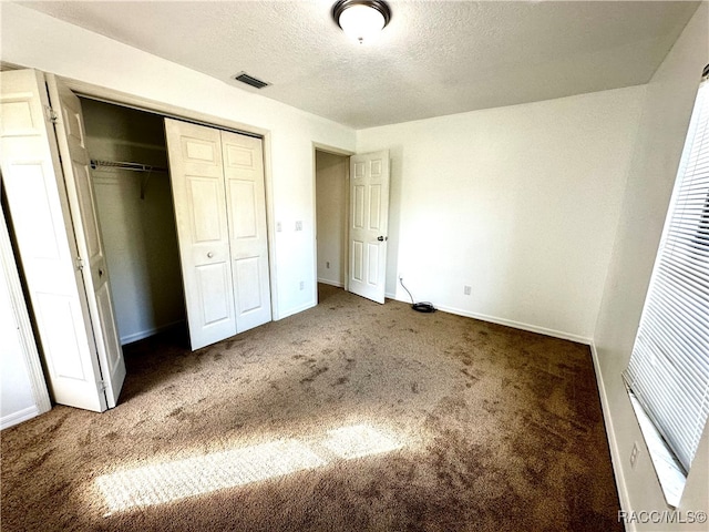 unfurnished bedroom with carpet floors, a textured ceiling, and a closet