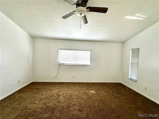 carpeted spare room with vaulted ceiling, ceiling fan, and a textured ceiling