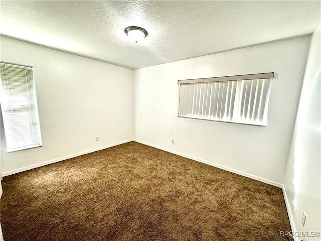 empty room featuring dark colored carpet and a textured ceiling