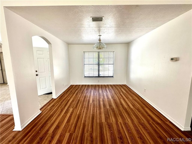 3150 W Mustang Blvd, Beverly Hills, FL 34465 - empty room with wood finished floors, arched walkways, a textured ceiling, and baseboards