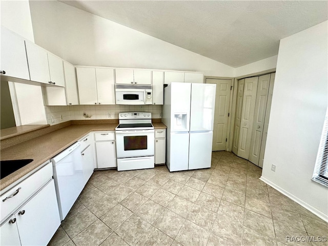 kitchen featuring lofted ceiling, white appliances, backsplash, white cabinets, and light tile patterned flooring