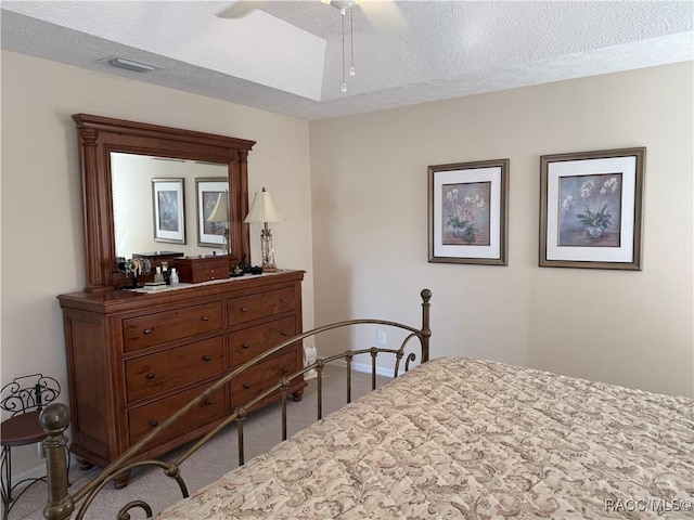 bedroom featuring ceiling fan, light colored carpet, and a textured ceiling