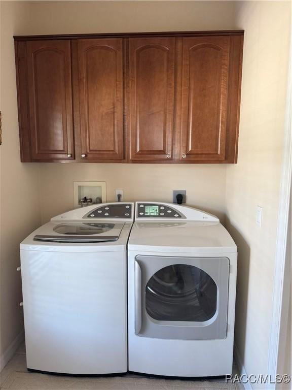 laundry room featuring separate washer and dryer and cabinets