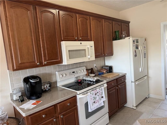 kitchen with tasteful backsplash, light tile patterned floors, and white appliances