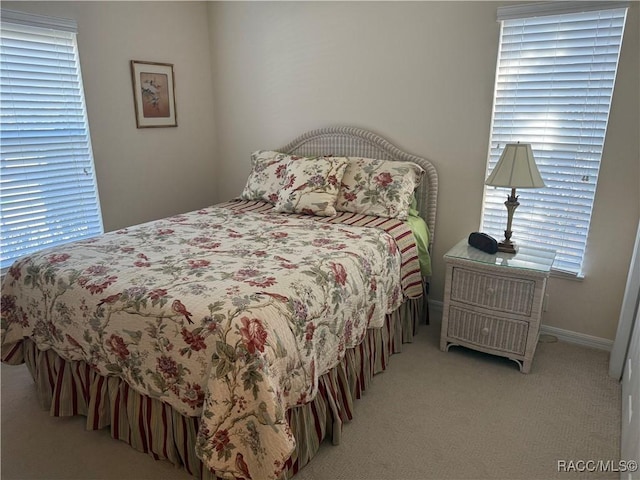 bedroom with multiple windows and light carpet