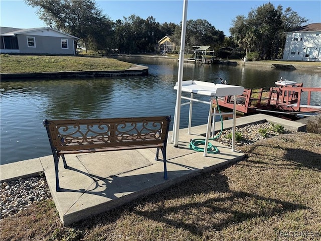 dock area with a lawn and a water view