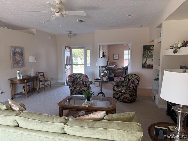 living room featuring ceiling fan, light colored carpet, and a textured ceiling