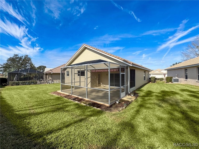 rear view of house with central AC unit, glass enclosure, and a lawn