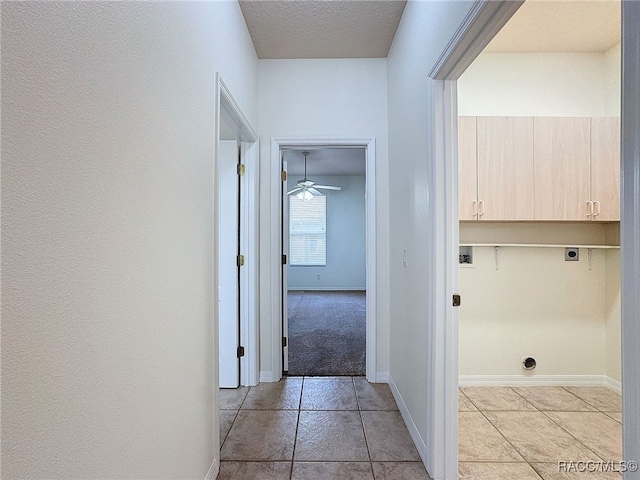 corridor featuring light tile patterned floors and a textured ceiling