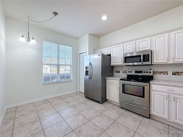 kitchen featuring pendant lighting, a notable chandelier, stainless steel appliances, and white cabinets