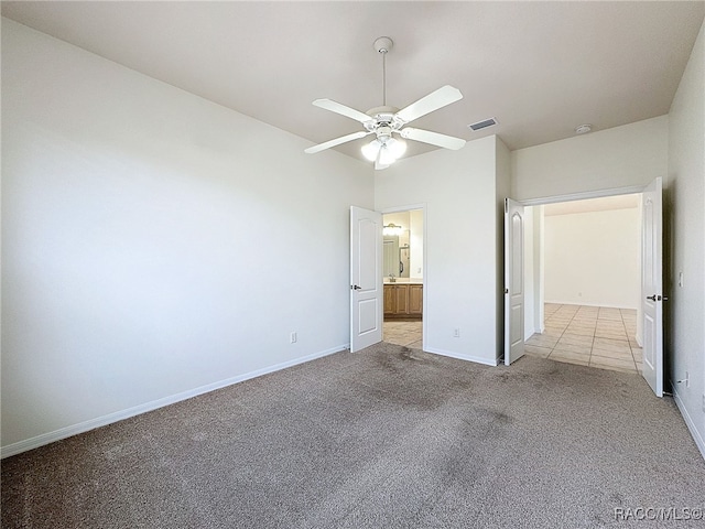 unfurnished bedroom with ensuite bathroom, light carpet, and ceiling fan