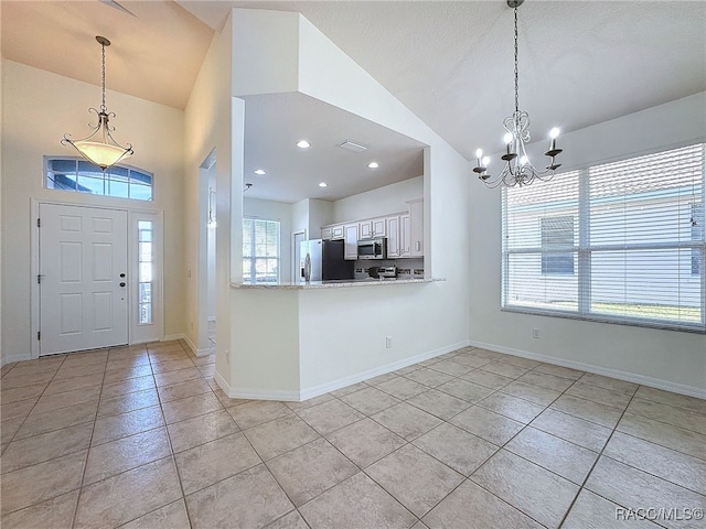 tiled entrance foyer with an inviting chandelier and vaulted ceiling