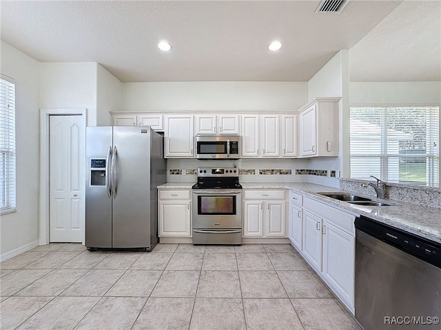 kitchen featuring appliances with stainless steel finishes, sink, a wealth of natural light, and white cabinets