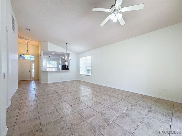 unfurnished living room with lofted ceiling, ceiling fan with notable chandelier, and light tile patterned floors