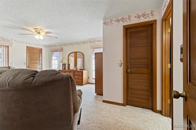 bedroom with light carpet, two closets, a ceiling fan, a textured ceiling, and baseboards