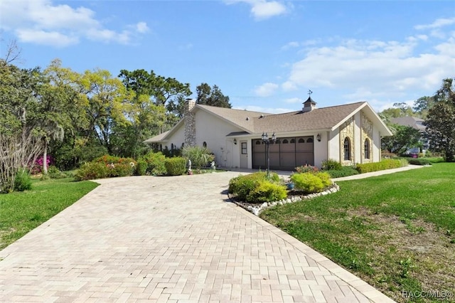 view of side of home featuring a lawn, an attached garage, decorative driveway, and stucco siding