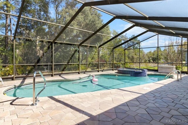 view of pool featuring glass enclosure, a pool with connected hot tub, and a patio