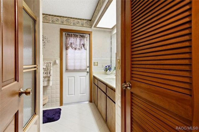 bathroom featuring an enclosed shower, toilet, tile walls, and vanity