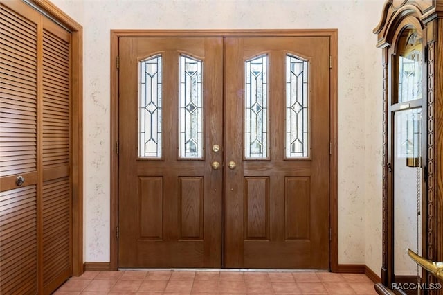 entryway featuring light tile patterned floors, wallpapered walls, and baseboards