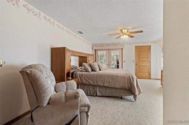 bedroom with access to exterior, light colored carpet, visible vents, and a textured ceiling