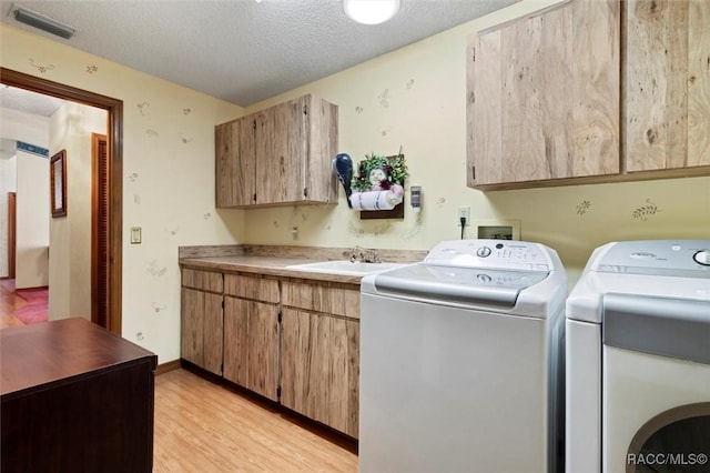 laundry room with light wood-type flooring, visible vents, washer and dryer, a sink, and cabinet space