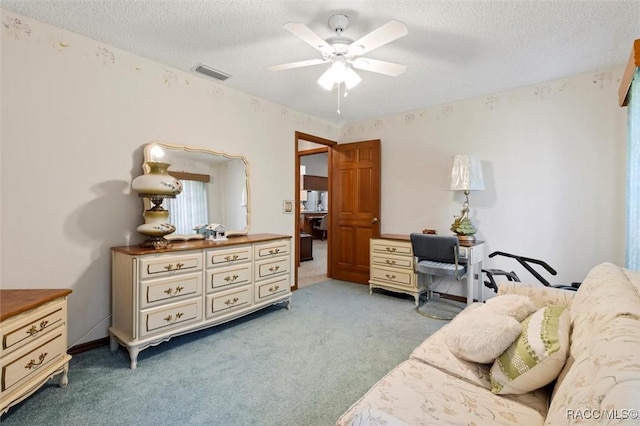 carpeted bedroom with visible vents, a textured ceiling, and a ceiling fan