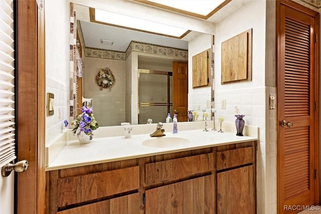 full bathroom with vanity, tile walls, a stall shower, and a closet