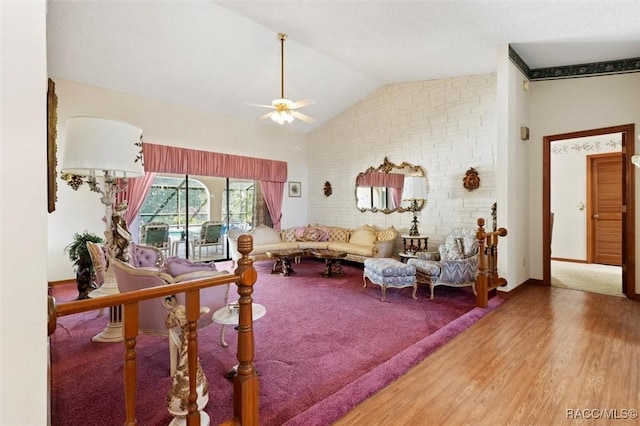 living area with baseboards, wood finished floors, a ceiling fan, and vaulted ceiling