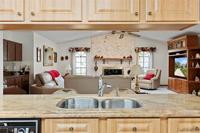 kitchen featuring vaulted ceiling, a fireplace, open floor plan, and a sink