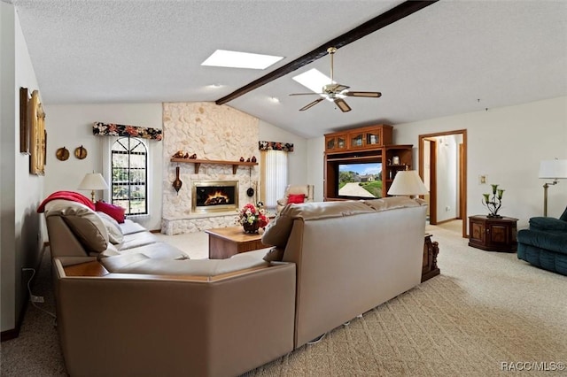 living area with lofted ceiling with skylight, a textured ceiling, carpet, a fireplace, and ceiling fan