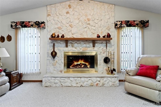 living area with a stone fireplace, lofted ceiling, and carpet floors