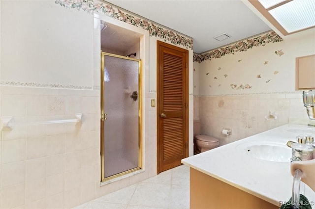 bathroom featuring a shower stall, wallpapered walls, a wainscoted wall, tile patterned floors, and tile walls