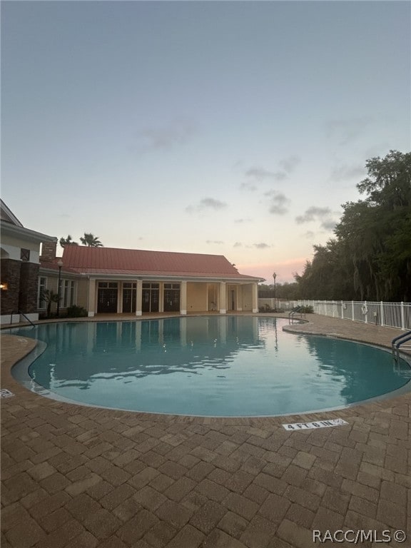 pool at dusk featuring a patio