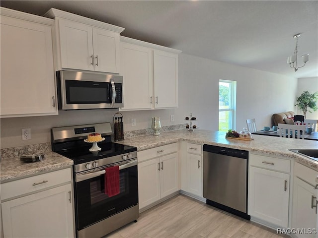1280 Heron Point Dr, Inverness, FL 34453 - kitchen with white cabinets, stainless steel appliances, light wood-style flooring, a peninsula, and hanging light fixtures
