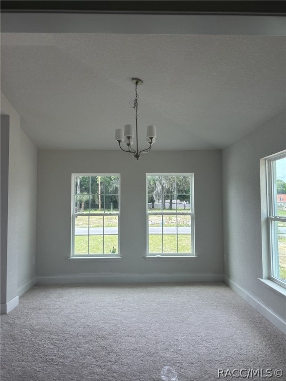 empty room with light carpet and a chandelier