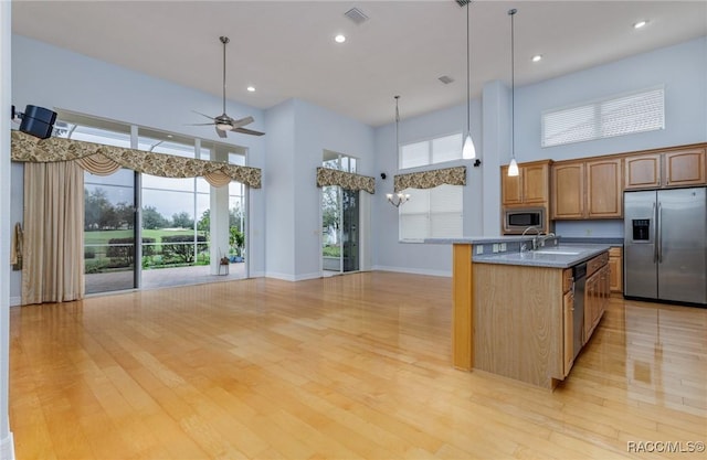 kitchen featuring appliances with stainless steel finishes, open floor plan, and hanging light fixtures