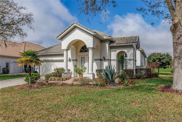 mediterranean / spanish-style home with concrete driveway, a front yard, a tile roof, and stucco siding