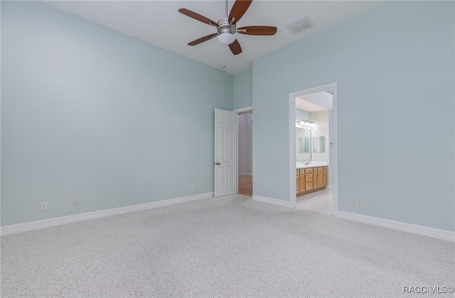 unfurnished bedroom with light colored carpet, a ceiling fan, baseboards, visible vents, and ensuite bath