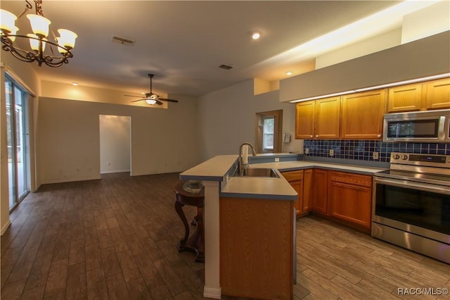 kitchen featuring pendant lighting, ceiling fan with notable chandelier, sink, appliances with stainless steel finishes, and wood-type flooring