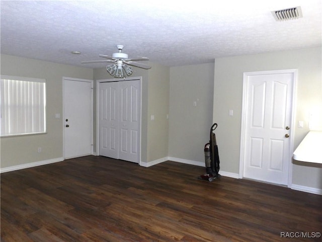 empty room featuring baseboards, a ceiling fan, visible vents, and dark wood-type flooring