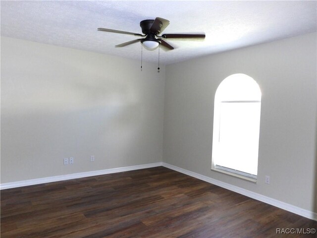 unfurnished room with dark wood-type flooring, baseboards, and ceiling fan