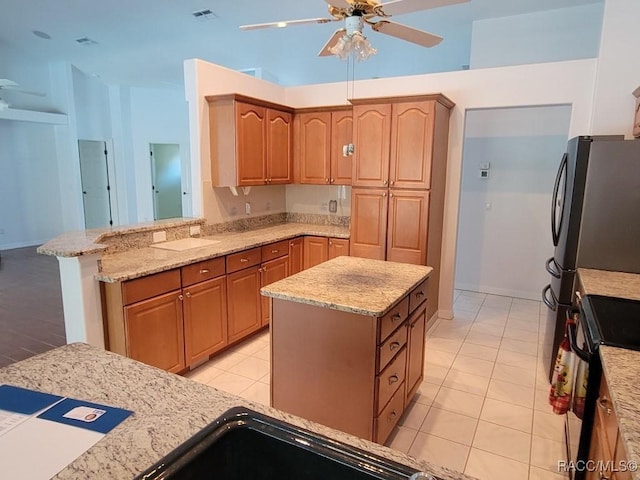 kitchen with kitchen peninsula, stove, light stone countertops, ceiling fan, and light tile patterned floors