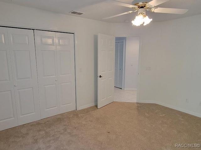 unfurnished bedroom featuring light carpet, a closet, and ceiling fan