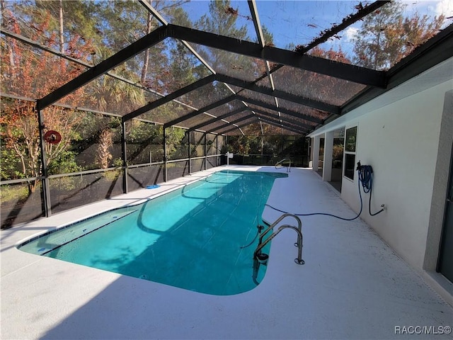 view of swimming pool with a patio area and a lanai