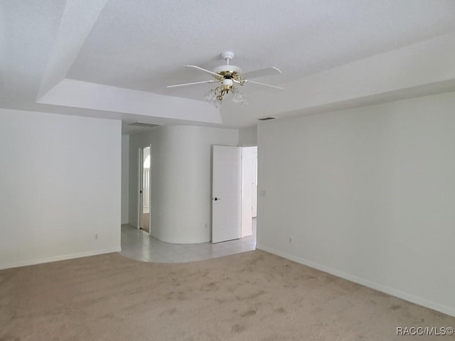 carpeted empty room with a tray ceiling and ceiling fan