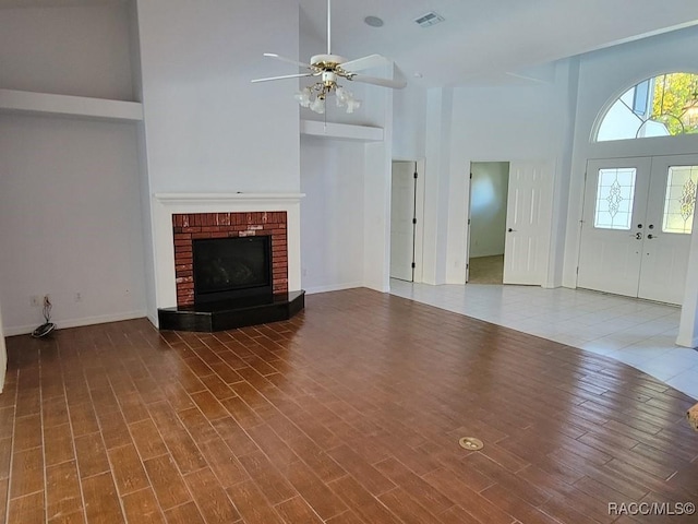 unfurnished living room with hardwood / wood-style floors, high vaulted ceiling, and a brick fireplace